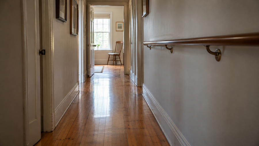 A narrow home hallway with a wooden handrail and a clear floor